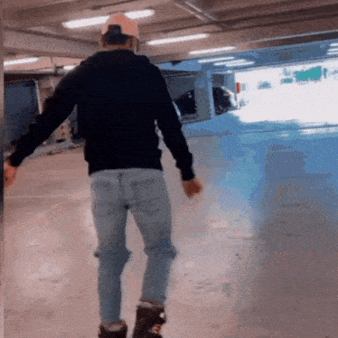 a man wearing a black sweatshirt and jeans is walking in a parking garage