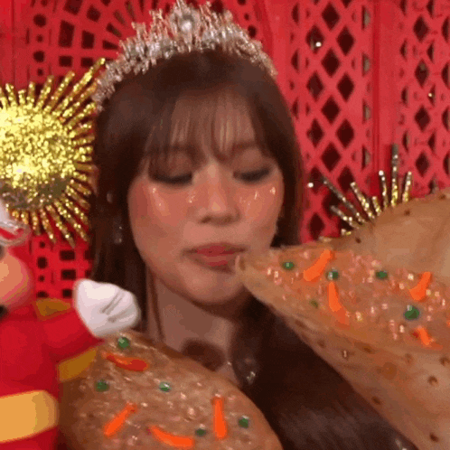 a woman wearing a tiara and a crown is eating a pizza