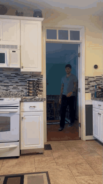 a man is standing in a kitchen looking out a door