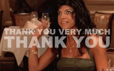 a woman is sitting at a table with a glass of wine and the words thank you very much thank you behind her
