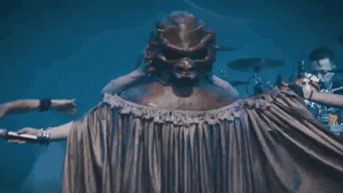 a group of people are dancing in front of a statue of a demon