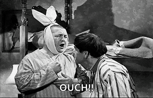 a man with a bandage on his head is being kissed by another man in a black and white photo .