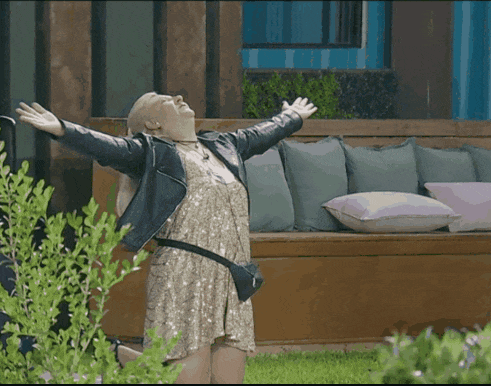 a woman in a sequined dress is standing in front of a couch with her arms outstretched