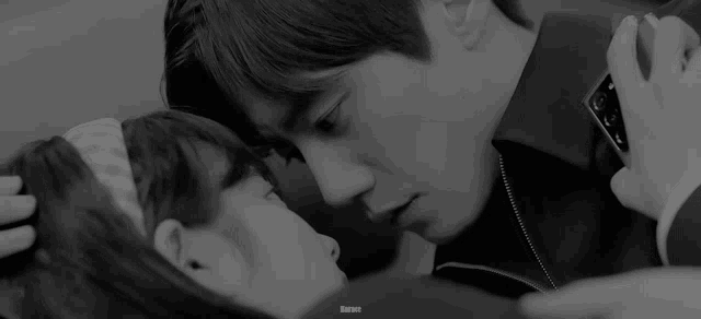 a black and white photo of a man kissing a woman on the forehead .