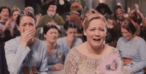 a group of women wearing tiaras are crying in a room
