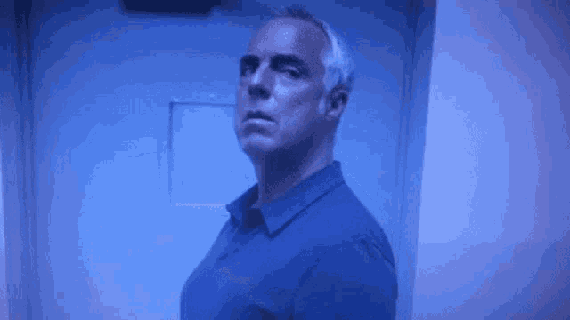 a man in a blue shirt is standing in front of a blue door .