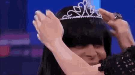 a woman is putting a tiara on another woman 's head .