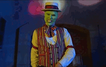 a man wearing a green mask and a hat is dancing in a room .
