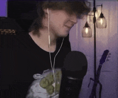 a young man wearing headphones and a black shirt is singing into a microphone .