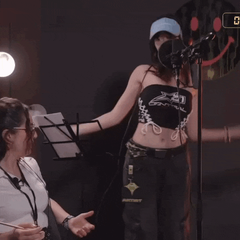 a woman wearing a black top that says central is standing in front of a microphone