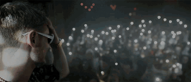 a man wearing sunglasses is looking at a crowd of people