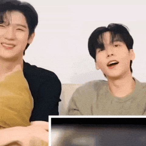 a couple of young men are sitting next to each other on a couch .