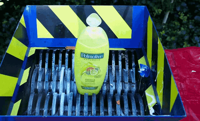 a bottle of palmolive shampoo is sitting in a shredder