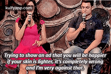 a man and a woman are sitting in front of a microphone .