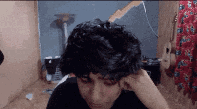 a close up of a person 's head with a guitar hanging on the wall behind them