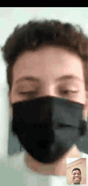 a man wearing a black face mask is on a video call