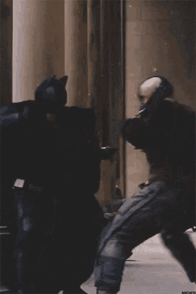a man in a mask is fighting another man in a black suit