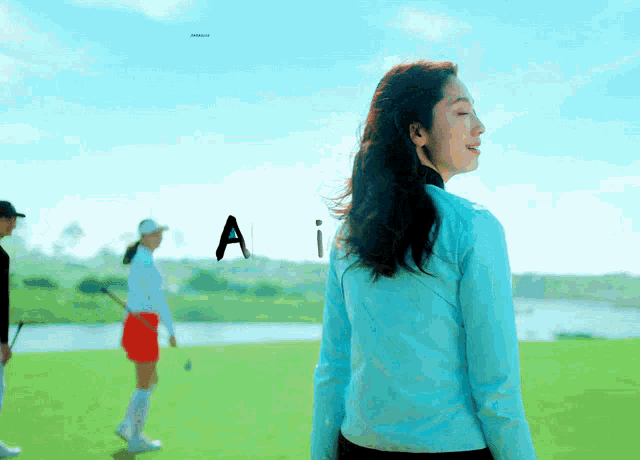 a woman in a blue shirt is standing on a golf course with the letter ai above her