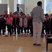 a man stands in front of a crowd of children