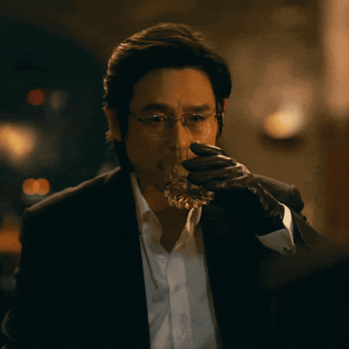a man in a suit holds a glass in his hand