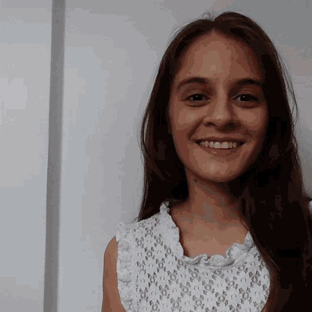 a woman with long hair wearing a white top smiles for the camera