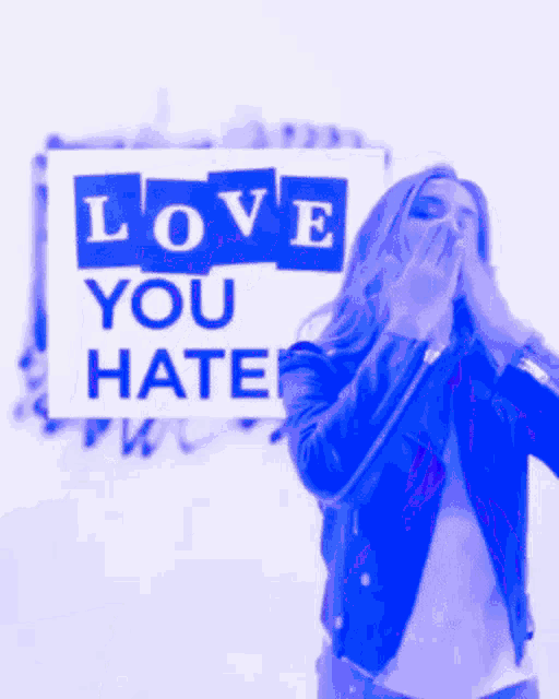 a woman in a leather jacket stands in front of a sign that says love you hate