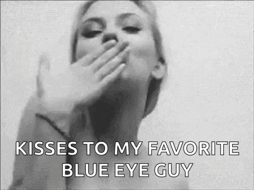 a black and white photo of a woman blowing a kiss to her blue eye guy .