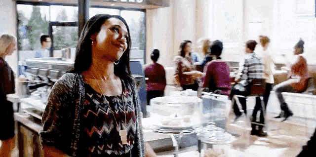 a woman is standing in a crowded room in a restaurant .
