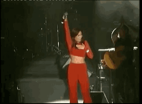 a woman in red pants is singing into a microphone on a stage .