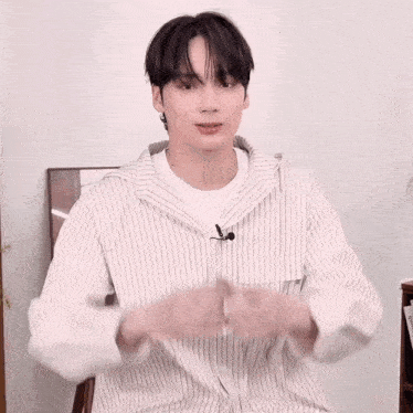 a man in a striped shirt is making a heart with his hands