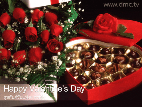 a red heart shaped box of chocolates sits next to a bouquet of red roses