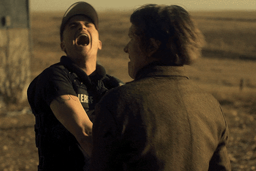 a man wearing a sheriff 's uniform is laughing with another man