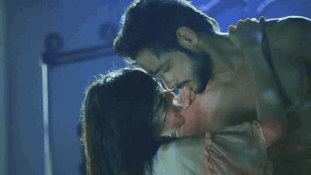 a man and a woman are kissing with a blue background