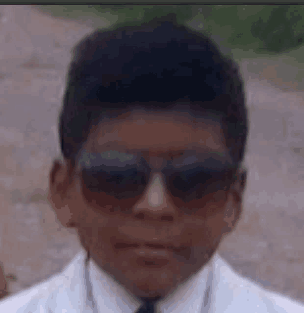 a close up of a young boy wearing sunglasses and a white suit .