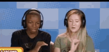 a man and a woman wearing headphones are sitting next to each other with a sign that says 1 second