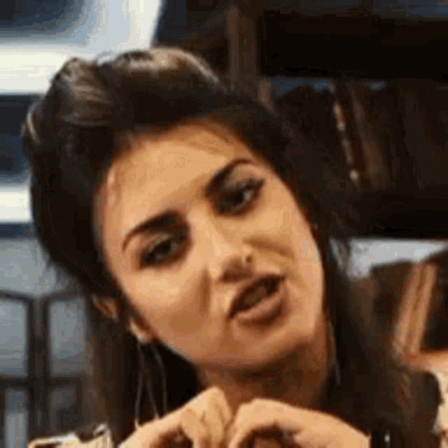 a close up of a woman making a funny face and making a heart shape with her hands .