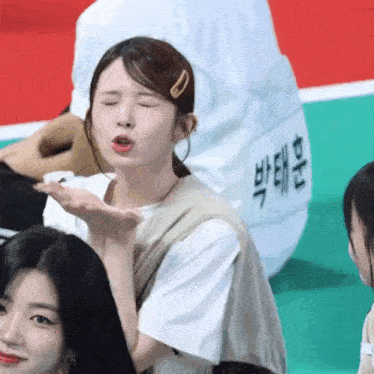 a woman blowing a kiss while wearing a white shirt that says ' bae ' on it