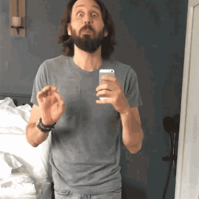 a man with a beard is taking a picture of himself in a mirror