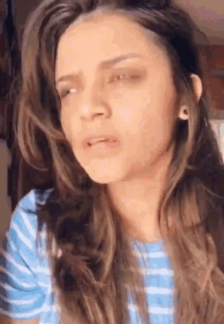 a woman with long hair is wearing a blue striped shirt .