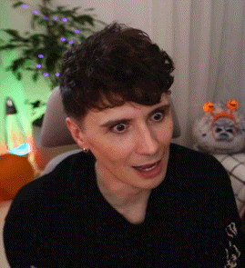 a young man is sitting in a chair and making a funny face in front of a christmas tree .