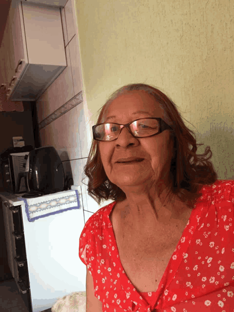 an older woman wearing glasses and a red shirt smiles for the camera