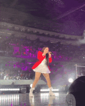 a woman singing into a microphone in front of a crowd at a concert