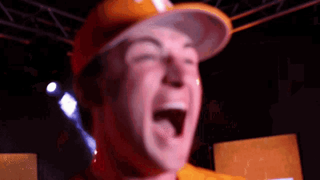 a man wearing a hard hat is laughing with his mouth wide open
