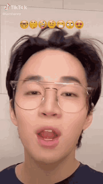 a young man wearing glasses and a black shirt has a tiktok sticker on his face