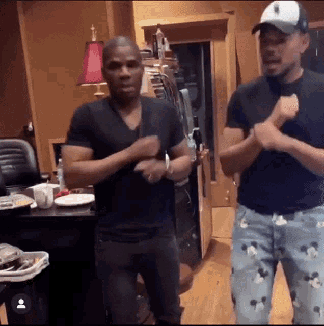 two men are standing next to each other in a room and dancing