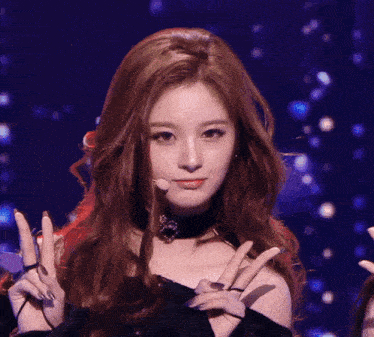 a woman with long red hair giving a peace sign in front of a microphone