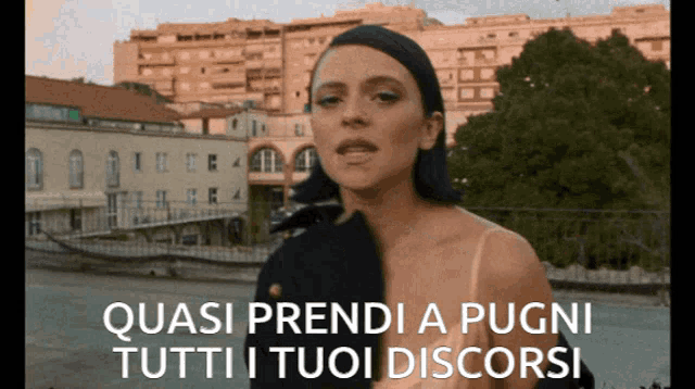 a woman is standing in front of a building with the words quasi prendi a pugni tutti i tuoi discorsi