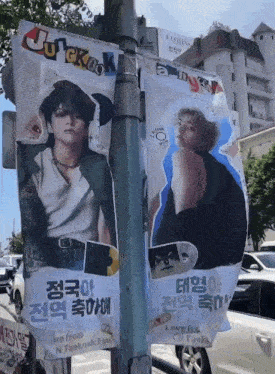 two posters on a pole with one that says jungkook on it