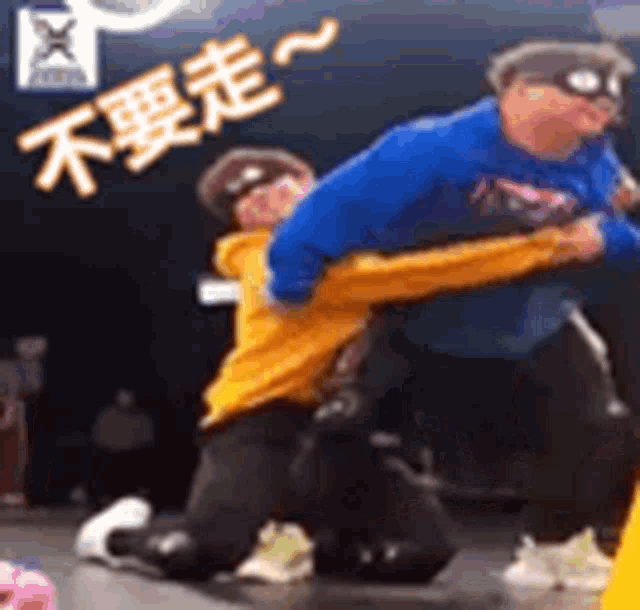 a man in a blue sweater is holding a woman in a yellow hoodie .