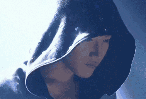 a man wearing a black hoodie with studs on it is looking down .